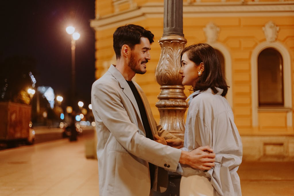 A couple sharing a romantic moment on a city street at night.