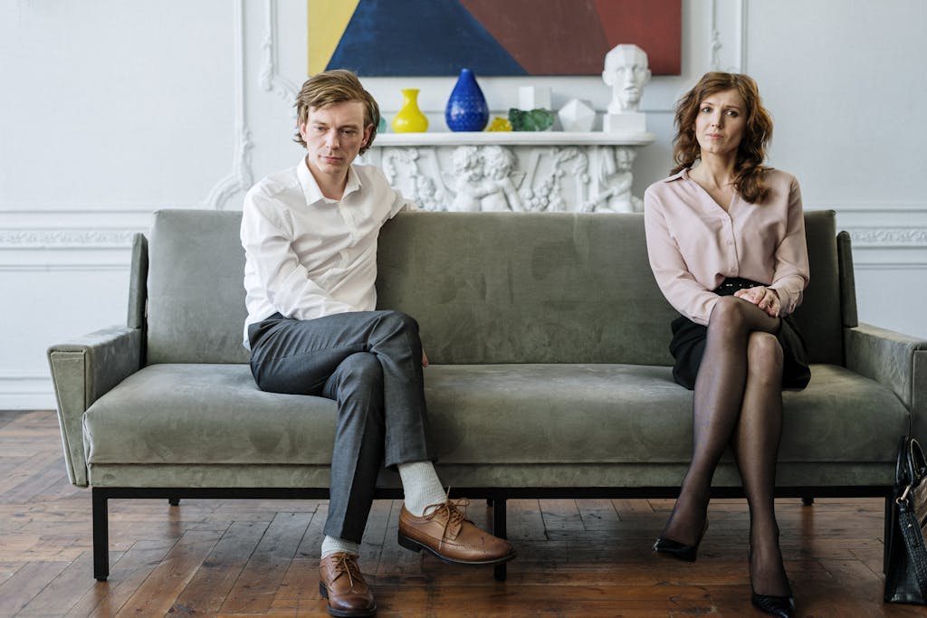A couple sitting apart during a counseling session, reflecting tension.