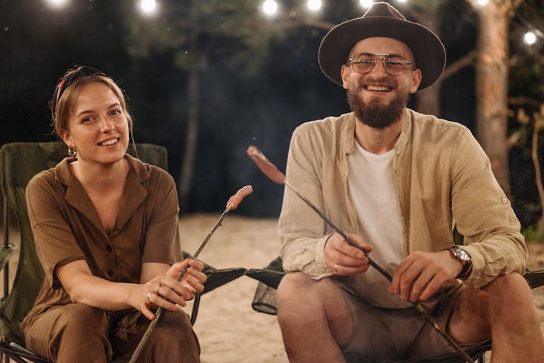 A joyful couple sitting by the campfire enjoying an evening outdoors together.