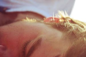 A serene close-up of a man sleeping in soft sunlight, capturing peaceful tranquility.