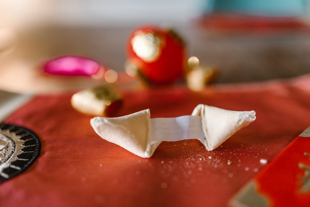 Close-up of a fortune cookie with message on a red tablecloth, symbolizing luck.