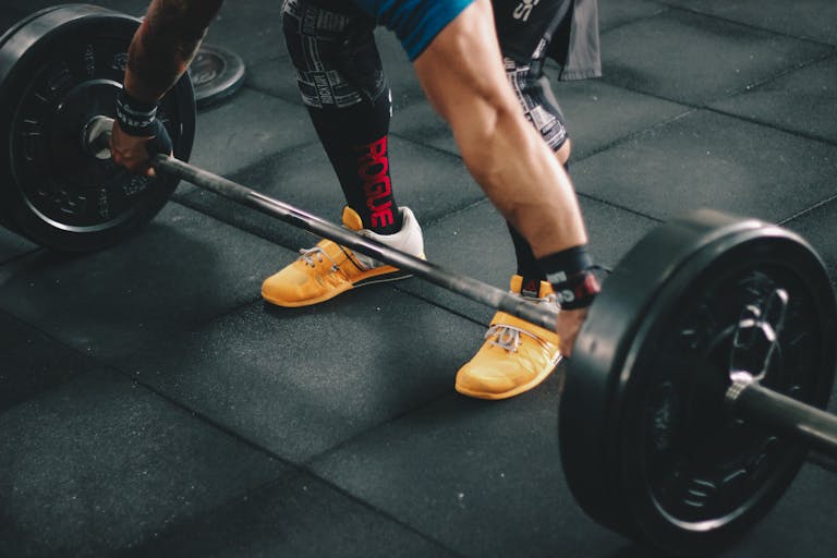 Close-up photo of a man lifting a barbell in the gym, showcasing strength and fitness.