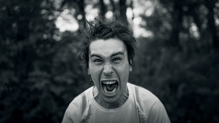 Intense black and white portrait showcasing a man yelling with a furious expression.