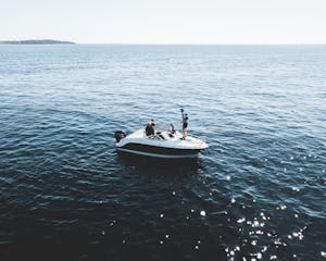 Motorboat with people cruising on the calm open sea under bright daylight.