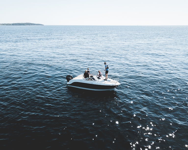 Motorboat with people cruising on the calm open sea under bright daylight.
