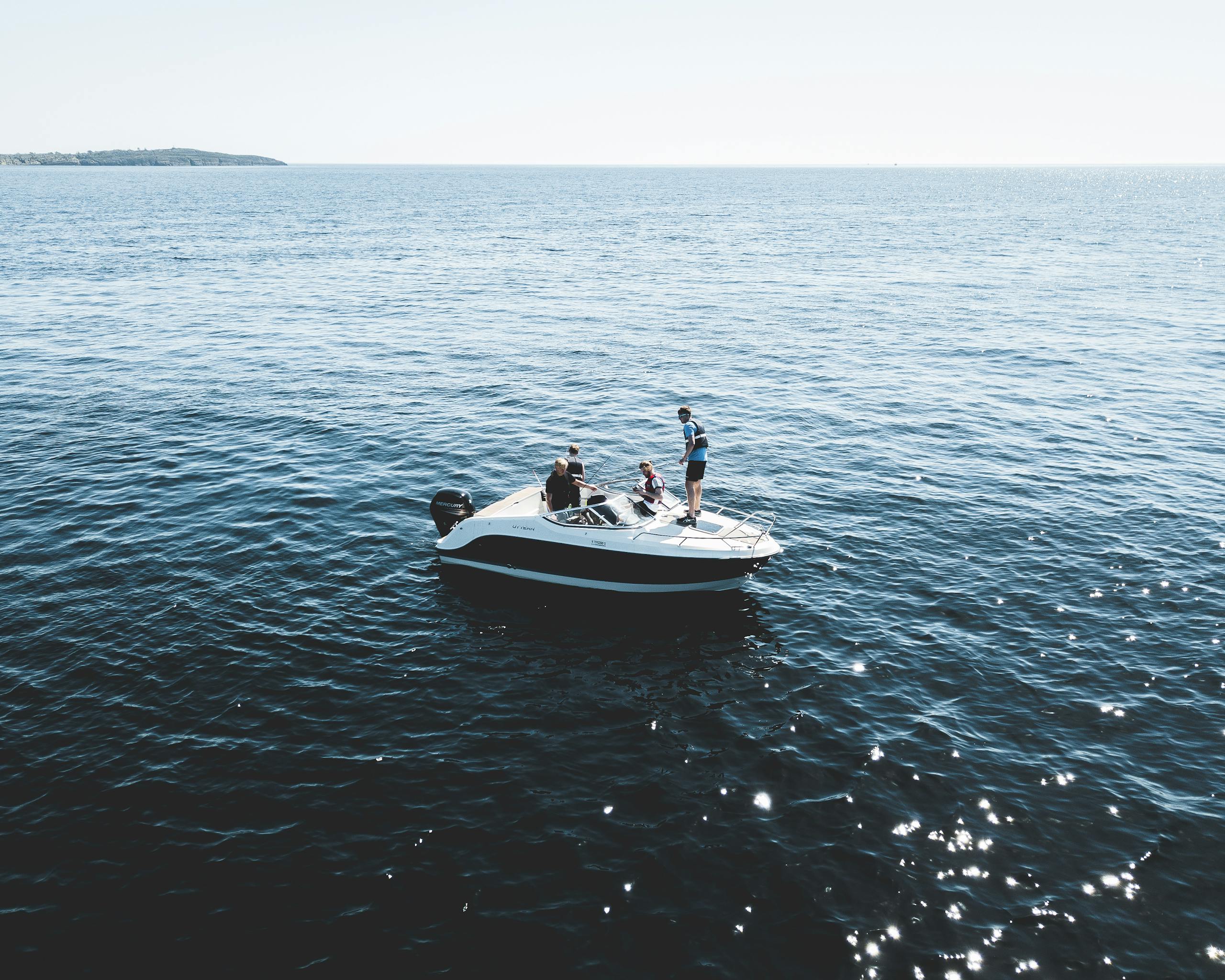 Motorboat with people cruising on the calm open sea under bright daylight.