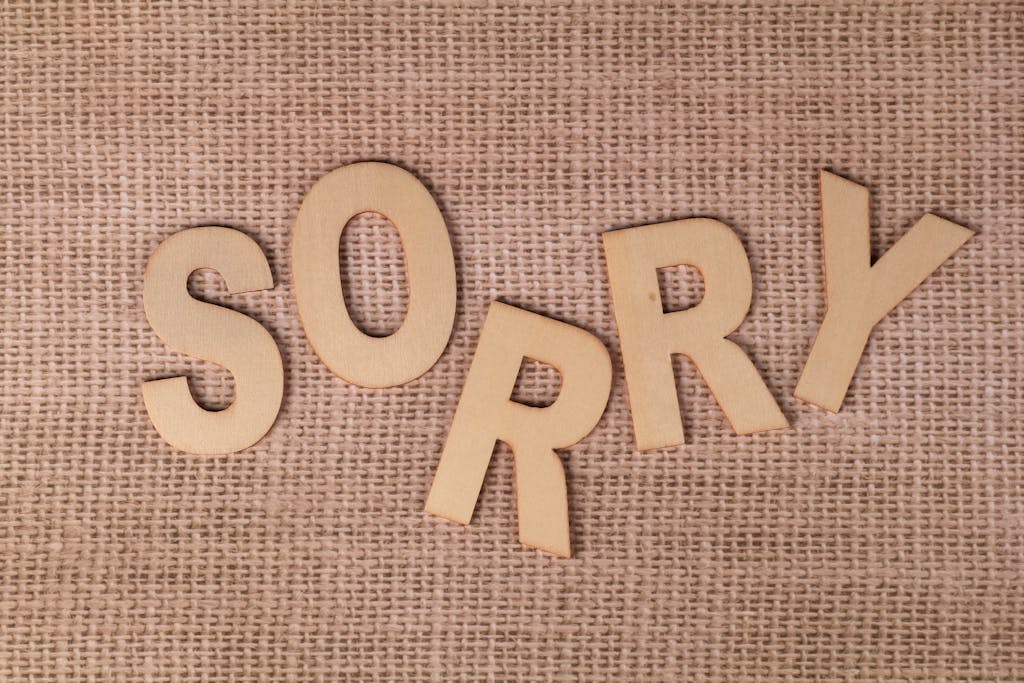 Wooden letters forming 'SORRY' on a burlap surface, offering a rustic apology vibe.
