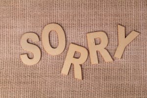Wooden letters forming 'SORRY' on a burlap surface, offering a rustic apology vibe.