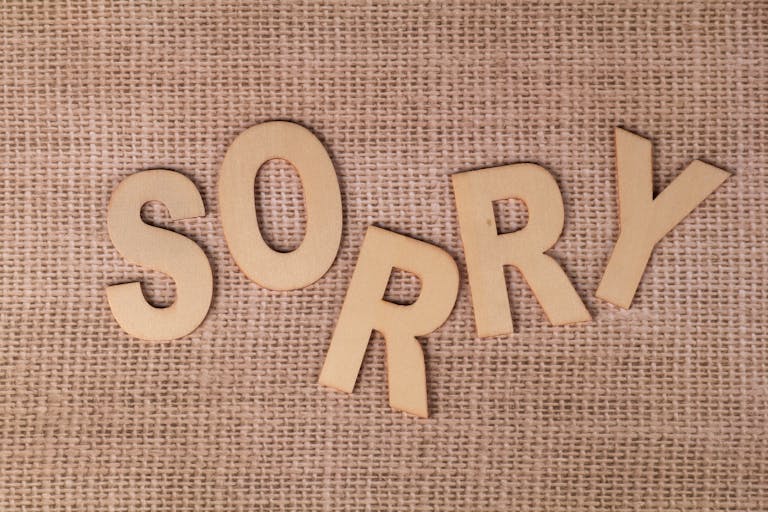 Wooden letters forming 'SORRY' on a burlap surface, offering a rustic apology vibe.