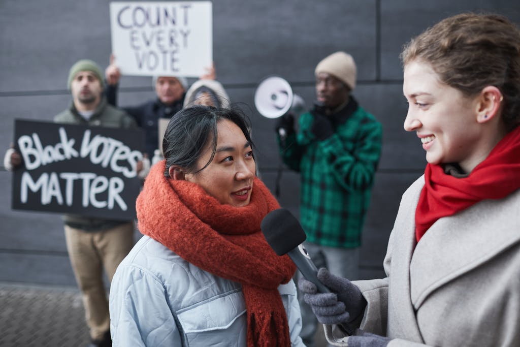 A reporter interviews a protestor at a street demonstration highlighting voting rights issues.