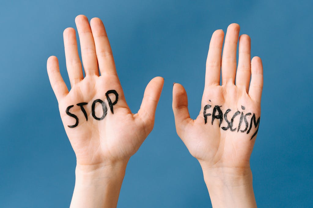 Close-up of hands with 'Stop Fascism' written, advocating against fascism.