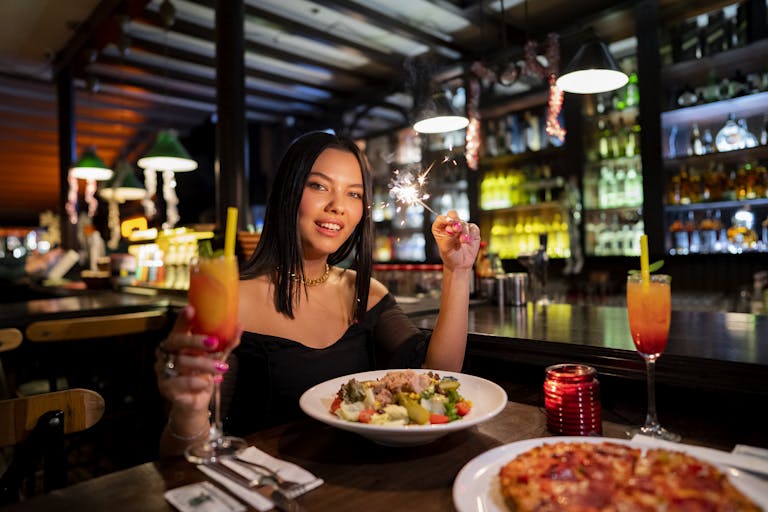 Woman celebrating with sparklers and cocktails in a cozy Istanbul bar.